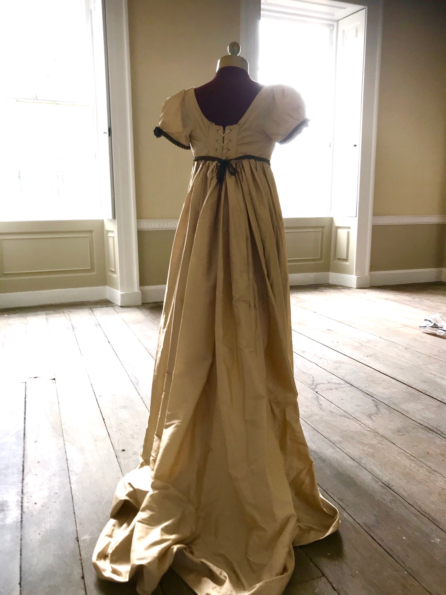A lady's Regency style day dress in cream silk with black lace trim (lacing at back). Ex London Festival Opera 'Cosi fan tutte'